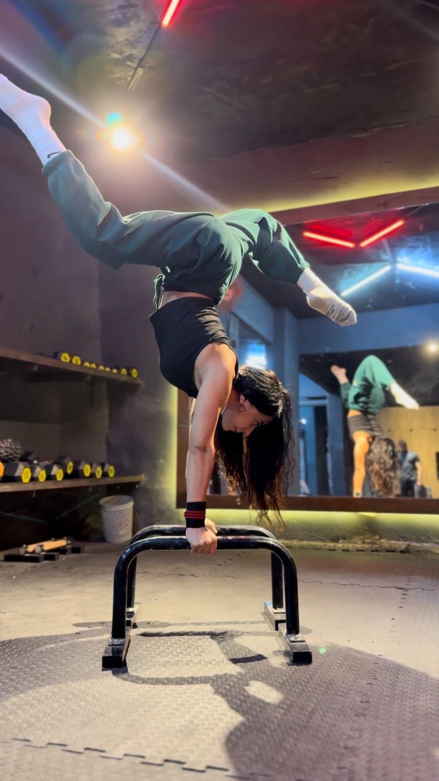 Yomna Bahaa holding a handstand on parallettes